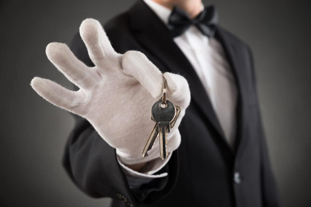 Estate staff member in formal uniform holding keys, symbolizing operational control and alignment between household and family office